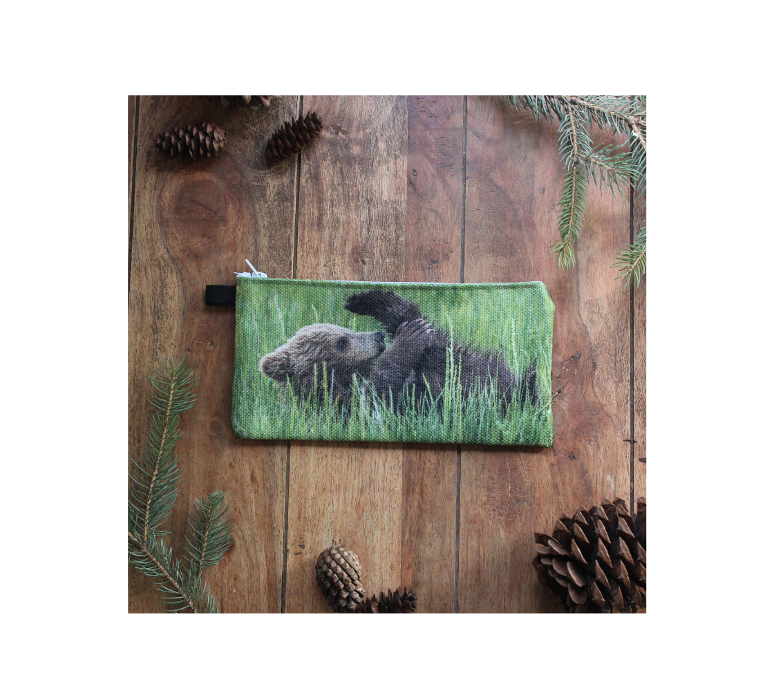 Durable double sided 9” x 4” canvas zippered pouch featuring real images of brown and tan grizzly bear cubs playing in a green field of grass. This side the bear cub is playing with his feet as if he was doing a hamstring stretch.