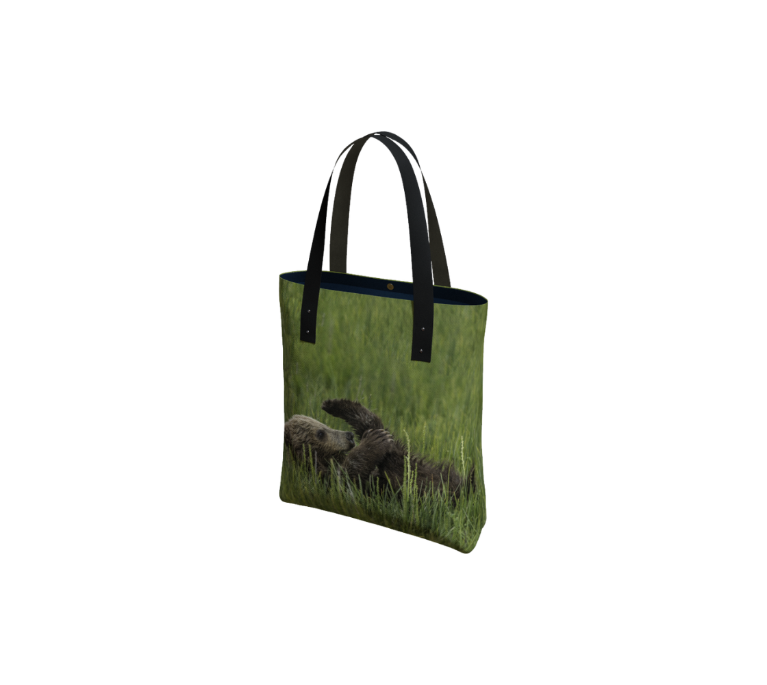 Durable canvas handbag with 1” vegan leather straps and magnetic closure with inside pockets. Features double sided real images grizzly bear cub with its leg in a yoga pose. Measures 16” x 13” x 3”.