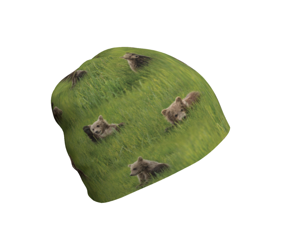 This is a photograph of a collage of brown bear cubs on a beanie. The background is bright green grass with little light brown colored bear cubs scattered throughout the beanie.