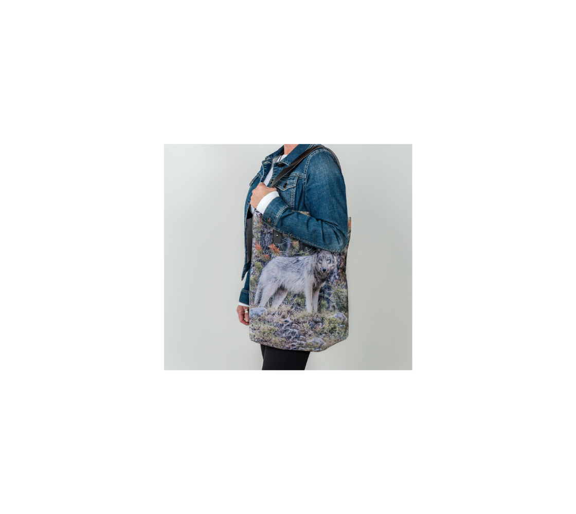 Durable canvas handbag with 1” vegan leather straps and magnetic closure with inside pockets. Features double sided real images of grey wolf in the spring. Measures 16” x 13” x 3”.