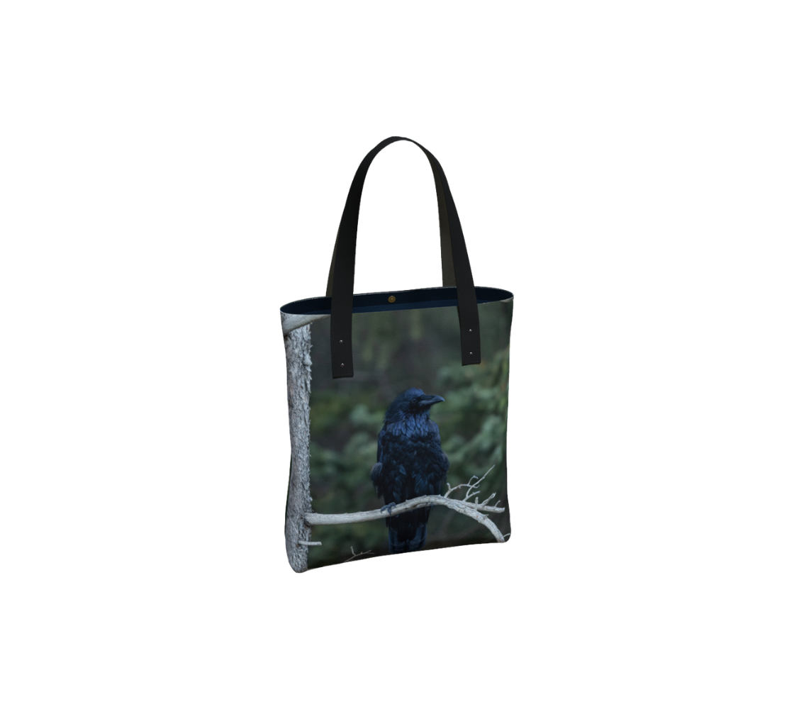 Durable canvas handbag with 1” vegan leather straps and magnetic closure with inside pockets. Features double sided real images of common raven. Measures 16” x 13” x 3”.