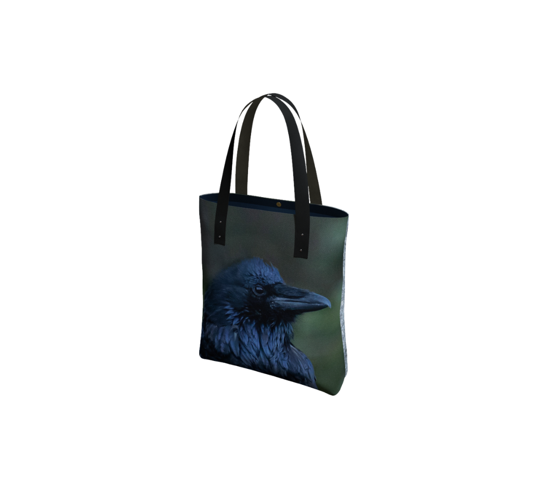 Durable canvas handbag with 1” vegan leather straps and magnetic closure with inside pockets. Features double sided real images of common raven. Measures 16” x 13” x 3”.
