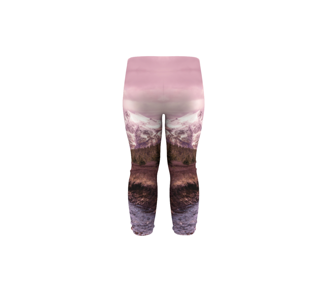 This is a back profile of a photo of a pink mountain sunset on a pair of infant leggings. The image is of a snow covered mountain in the far distance with a meandering stream winding its way through the fall colored willow and forest of evergreen trees towards the mountain. A special filter used when taking this photograph created an over all pink hue to the image that really accentuated the sunset light at the time.