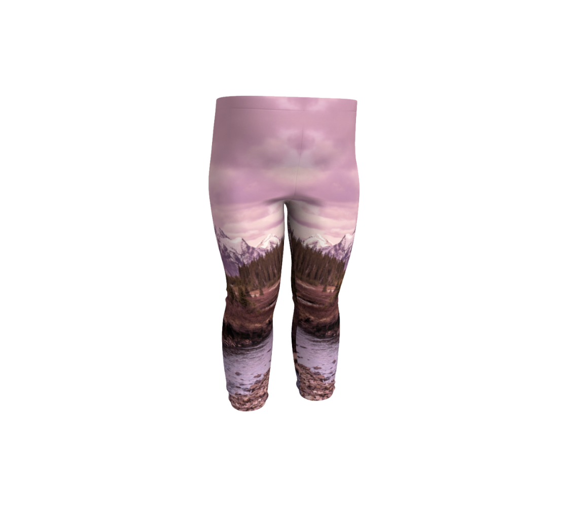 This is a front profile of a photo of a pink mountain sunset on a pair of infant leggings. The image is of a snow covered mountain in the far distance with a meandering stream winding its way through the fall colored willow and forest of evergreen trees towards the mountain. A special filter used when taking this photograph created an over all pink hue to the image that really accentuated the sunset light at the time.