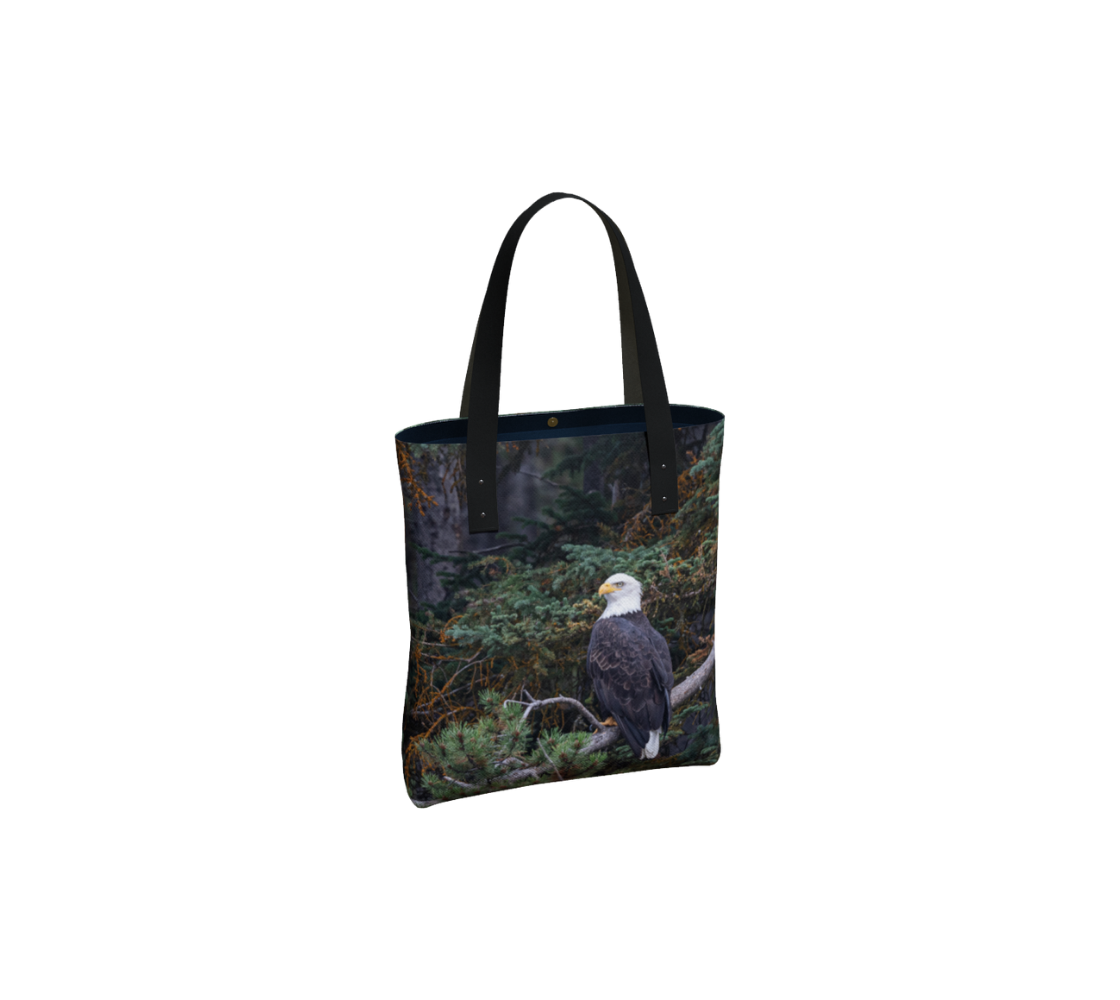 Durable canvas handbag with 1” vegan leather straps and magnetic closure with inside pockets. Features double sided real images of bald eagle in the trees. Measures 16” x 13” x 3”.