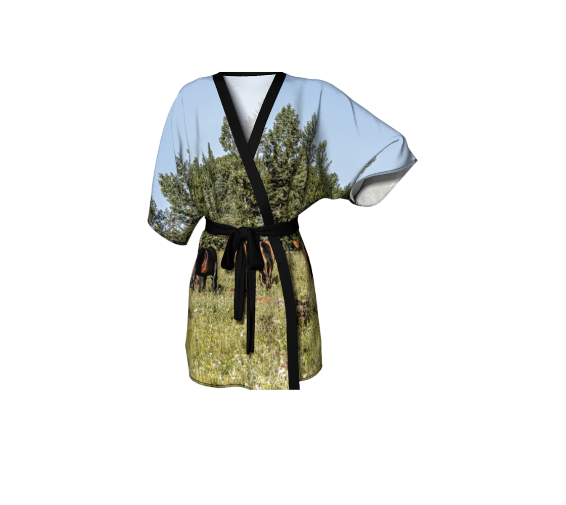 A front view of a kimono cover up with an image of a group of wild horses design with a blue and green background.