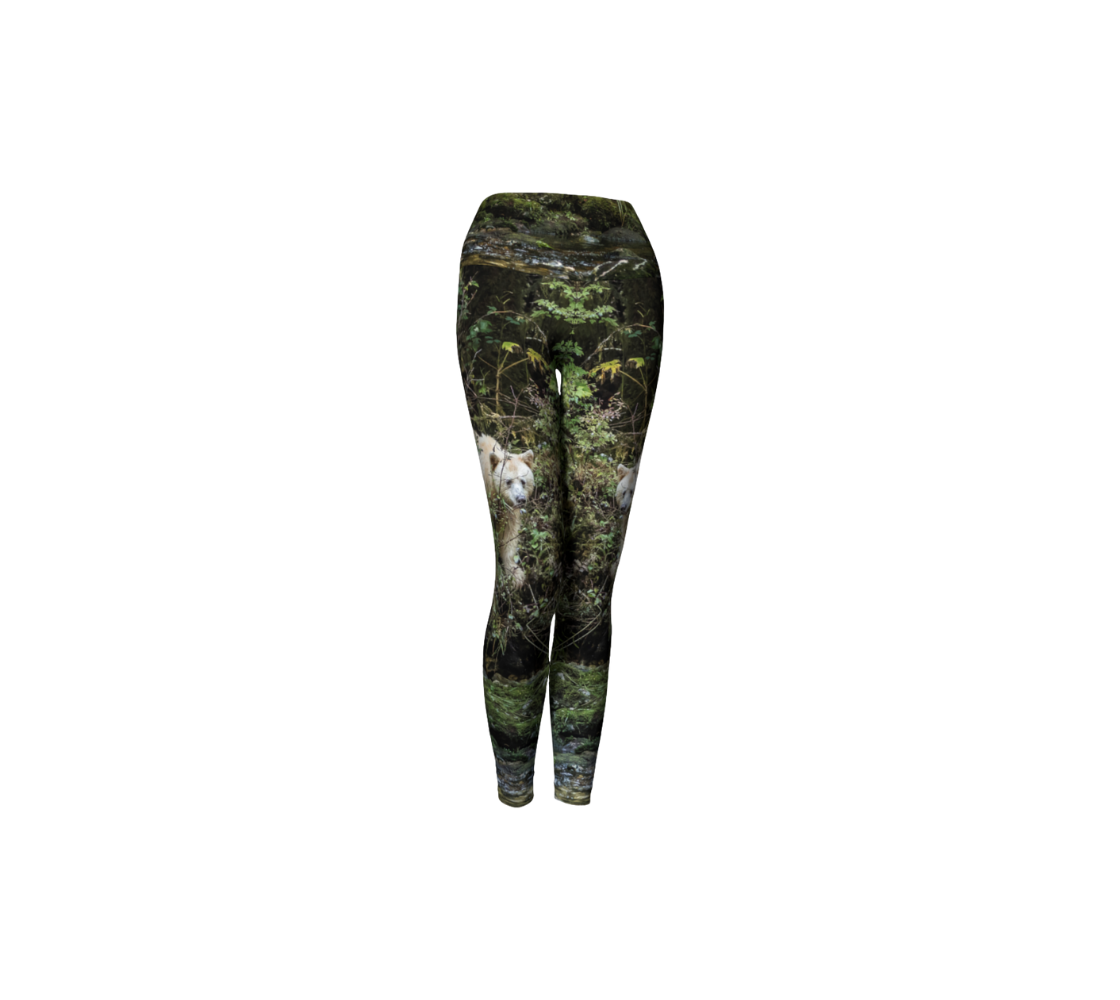 This is a front profile of a pair of yoga leggings featuring a spirit bear on each leg, with a 4.5 inch wide waistband. The background is green bushes and brown branches of the Great Bear Rainforest. The white spirit bear is stepping down out of the forest and is making her way to the stream below.oga leggings with a 4.5 inch high waist band. Front profile background green tree with a white spirit bear standing in the trees.